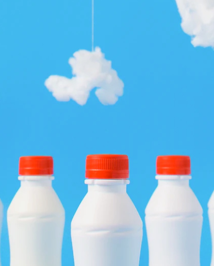 three small white milk bottles over blue background with small clouds